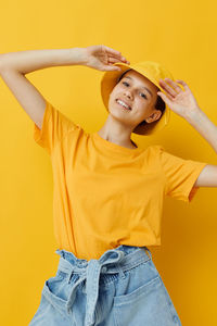 Portrait of smiling girl against yellow background