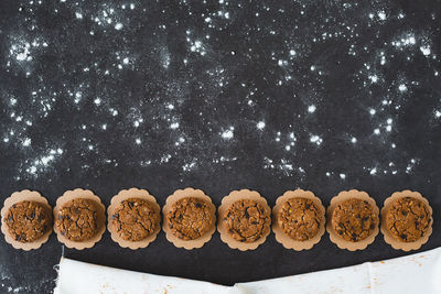 Directly above shot of chocolate chip cookies and rolling pin on black background