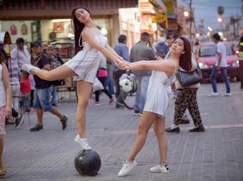 Woman and girl dancing on sidewalk in city