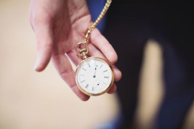 Close-up of hand holding clock against blurred background