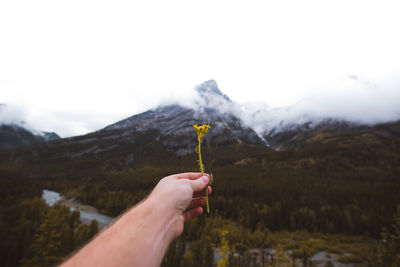 Person holding umbrella against mountain range