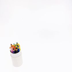 High angle view of multi colored pencils on table against white background