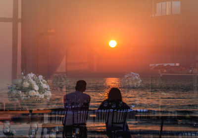 Reflection of sea on glass window during sunset