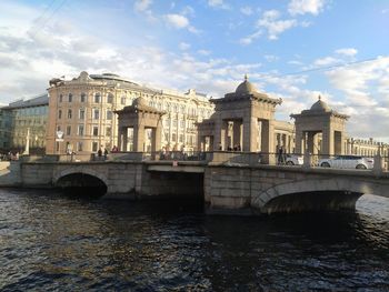 Arch bridge over river against cloudy sky