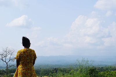 Rear view of woman standing on landscape against sky