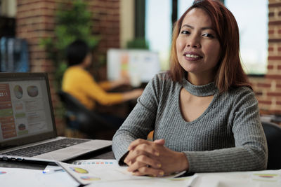 Portrait of young woman using laptop at table