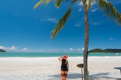 Woman standing on beach against blue sky