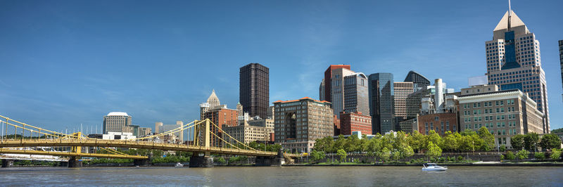 Bridge over river by buildings against sky in city