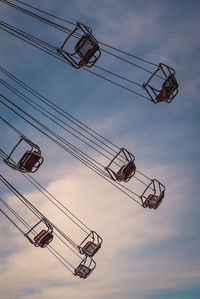 Low angle view of chain swing ride against cloudy sky