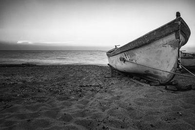 Boat moored on beach against sky