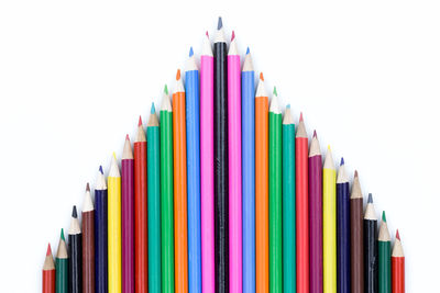 Close-up of multi colored pencils in row against white background