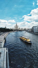 Nautical vessel on river by buildings against sky