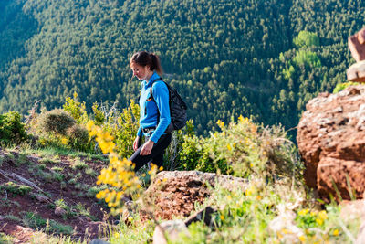 Side view of man on rock in forest