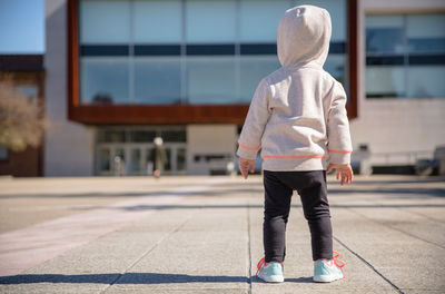 Rear view of boy standing on footpath