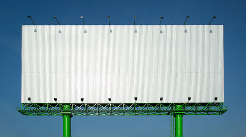 Low angle view of bird perching on metallic structure against sky