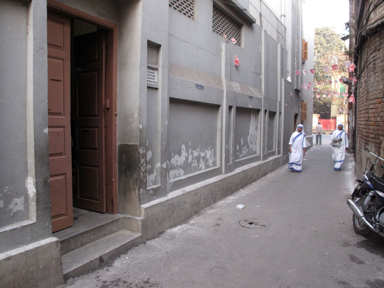 REAR VIEW OF PEOPLE WALKING ON STREET AGAINST BUILDINGS