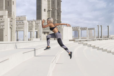 Full length of young woman with arms raised against sky