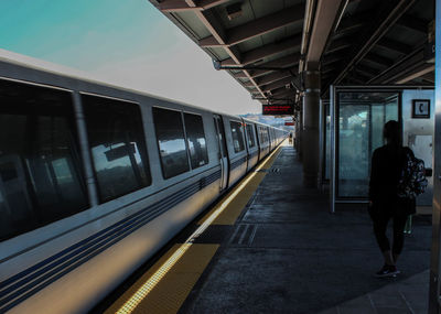 Rear view of woman standing at railroad station