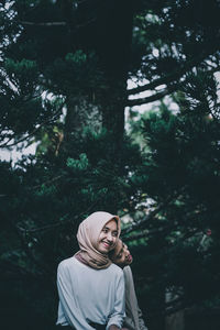 Portrait of smiling young woman and man standing against trees