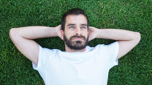 Portrait of young man lying on grassy field