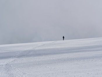 Person on snowcapped mountain against sky