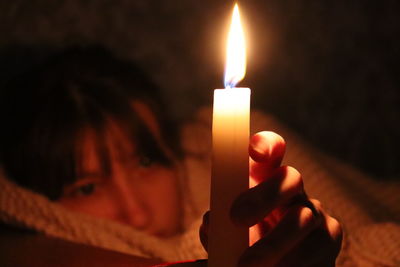 Close-up of hand holding lit candle