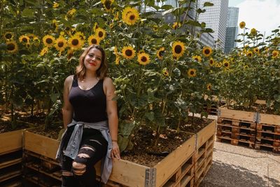 Portrait of a young woman standing against plants