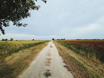 Road amidst field against sky