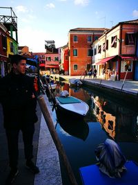 People on canal in city against sky