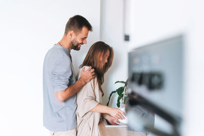 Happy young family couple in love washes dishes in bright modern kitchen at home