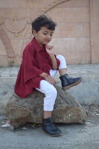 Portrait of boy looking away while sitting on rock