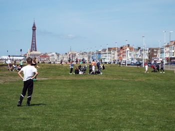 People playing soccer on field in city against sky