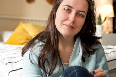 Middle aged woman in pajamas and sleep mask sitting relaxed on bed at home