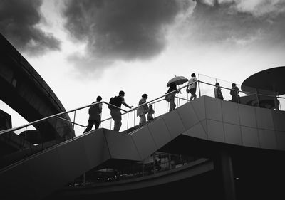 Low angle view of people on staircase against sky