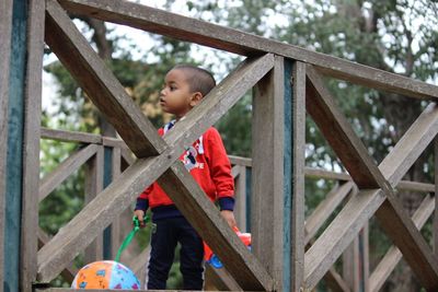 Low angle view of boy standing on footbridge 