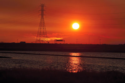 Silhouette electricity pylon against sky during sunset