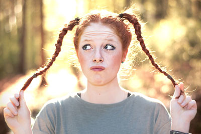 Woman making face while holding pigtail braids