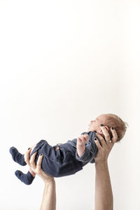 Hands of mother carrying baby boy against white background