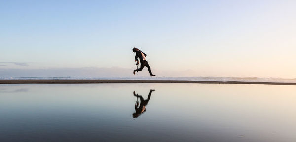 Man on sea against sky during sunset