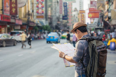 Man reading map while standing in city