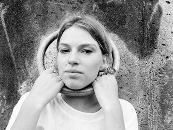 Portrait of young woman holding ring around neck against wall