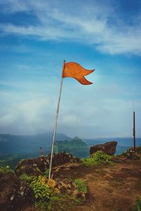 Low angle view of flag on rock against sky