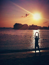 Silhouette of woman standing on beach at sunset