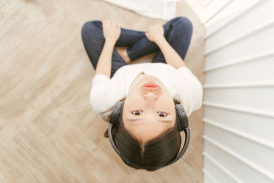 Directly above portrait of young woman listening to music at home