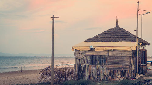 Hut on beach against sky during sunset