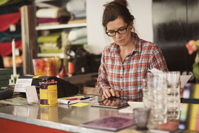 Owner using digital tablet at checkout counter in store