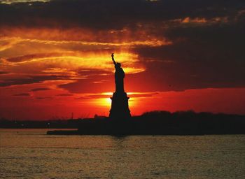 Silhouette of statue against cloudy sky during sunset