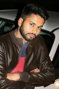 Portrait of young man sitting on car