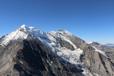 Scenic view of snowcapped mountains against clear blue sky on sunny day