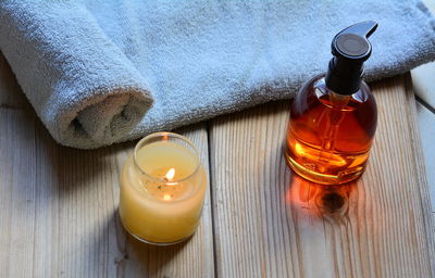 High angle view of tea light candle and oil bottle on table at beauty spa